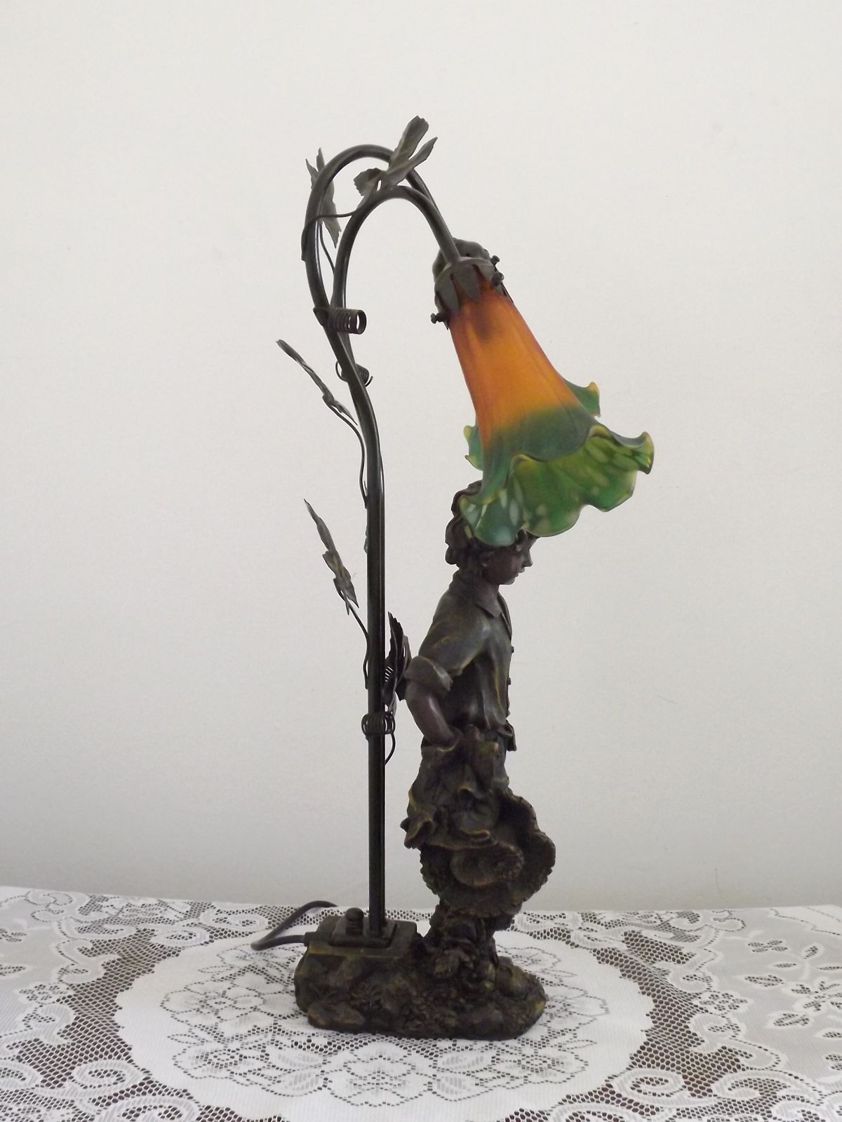 photo vintage Art Nouveau tafellamp met jongensbeeldje en tulpvormige kappen in amber en groen glas