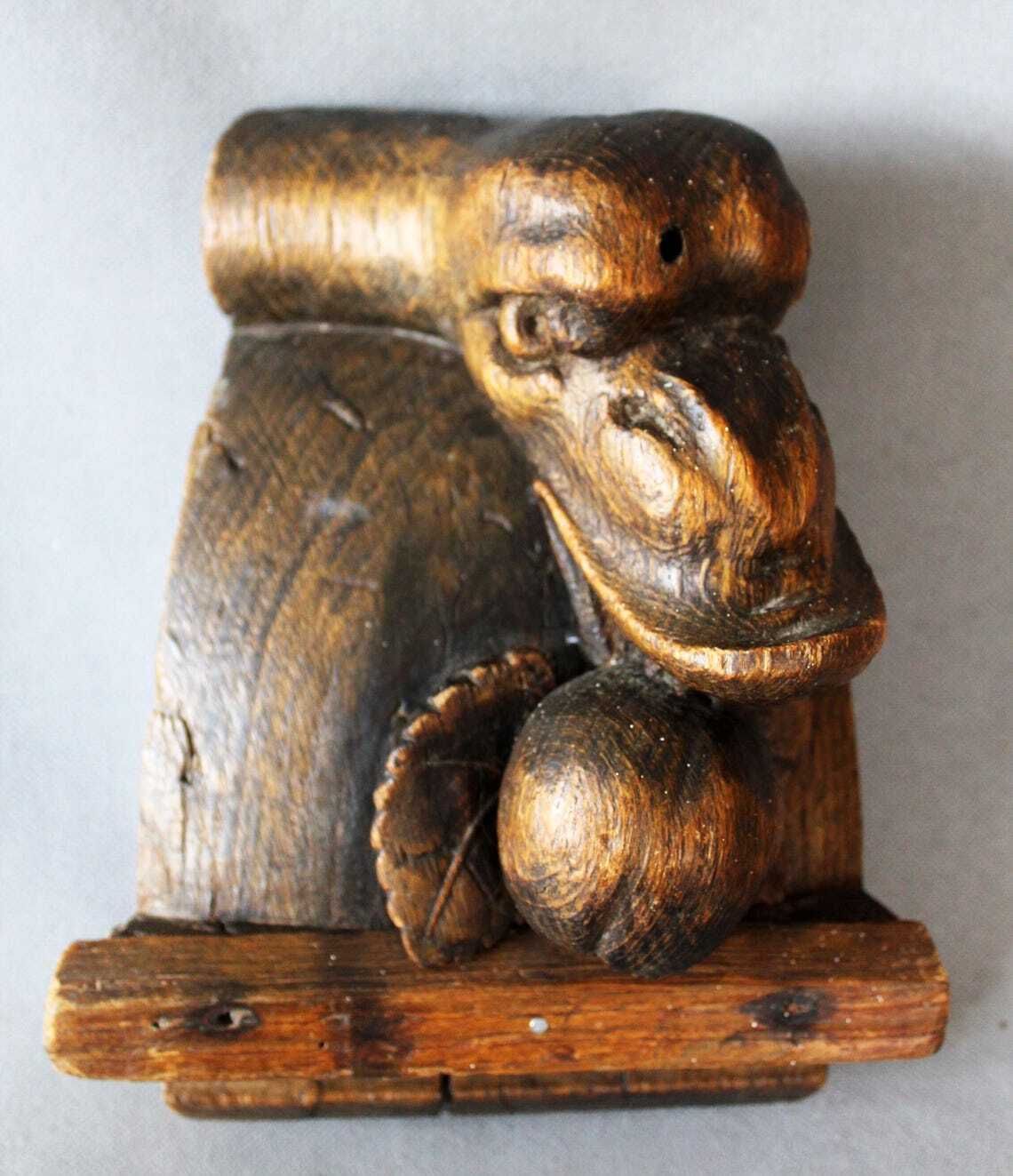 Groot antiek houten ornament in de vorm van een slangenkop met tanden die een appel of granaatappel eet, driedimensionaal, handgesneden, gotische architectuur photo for sale
