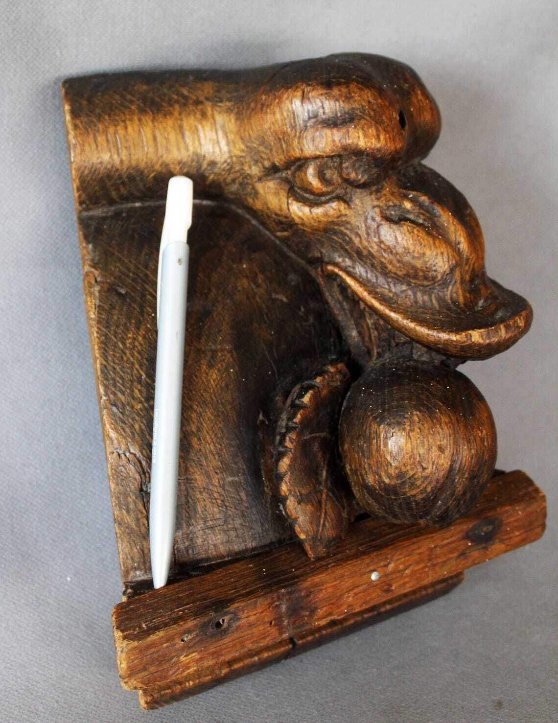 Groot antiek houten ornament in de vorm van een slangenkop met tanden die een appel of granaatappel eet, driedimensionaal, handgesneden, gotische architectuur photo Kunst
