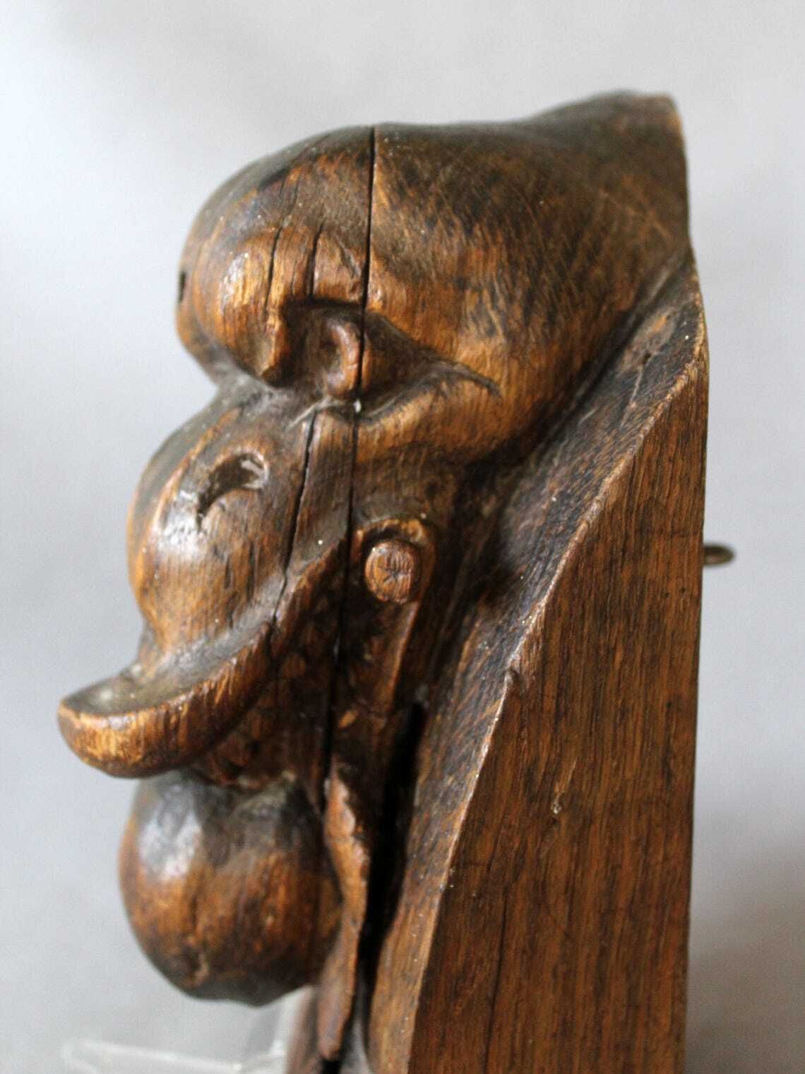 photo vinterior Groot antiek houten ornament in de vorm van een slangenkop met tanden die een appel of granaatappel eet, driedimensionaal, handgesneden, gotische architectuur