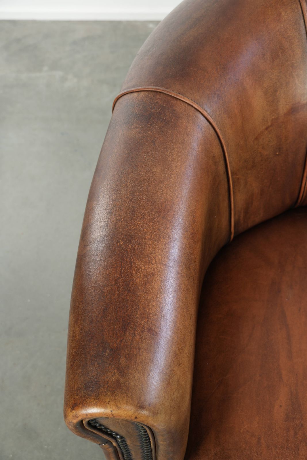 Stevige en karaktervolle clubfauteuil in schapenleer met een mooie patina, afgewerkt met decoratieve nagels. photo buy