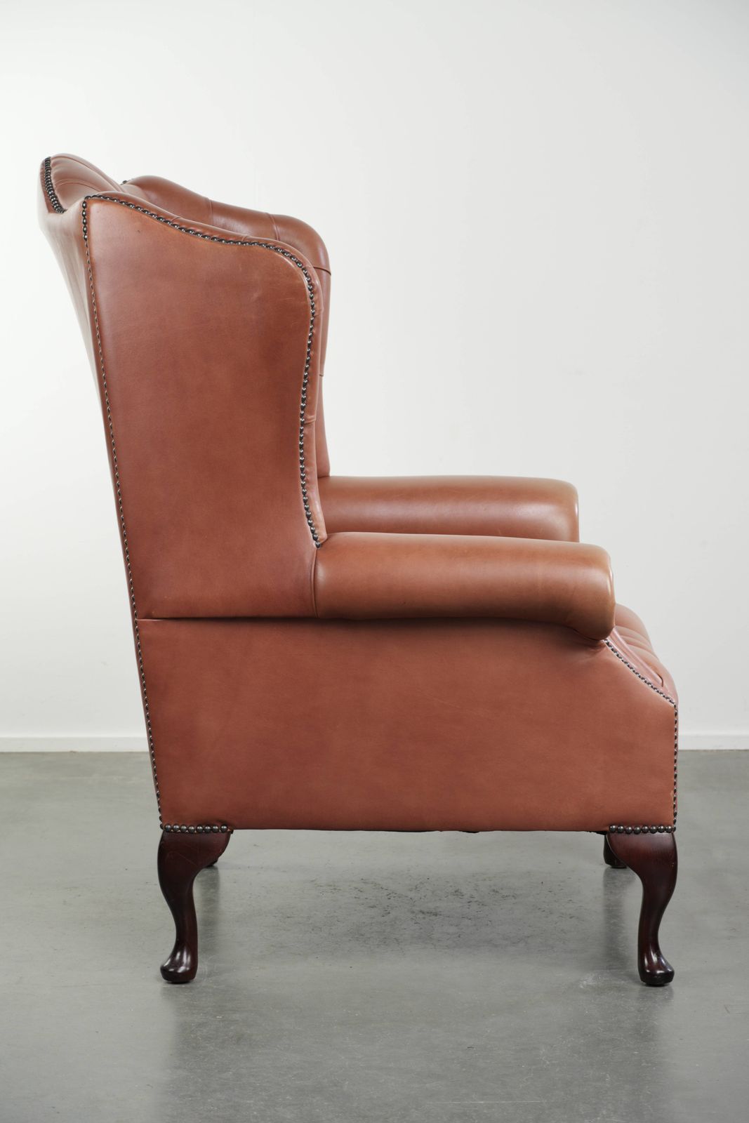 Klassieke Engelse Chesterfield-vleugelfauteuil met koeienhuid, knoopsluiting, mooie patina en fraaie kleuren. photo for sale