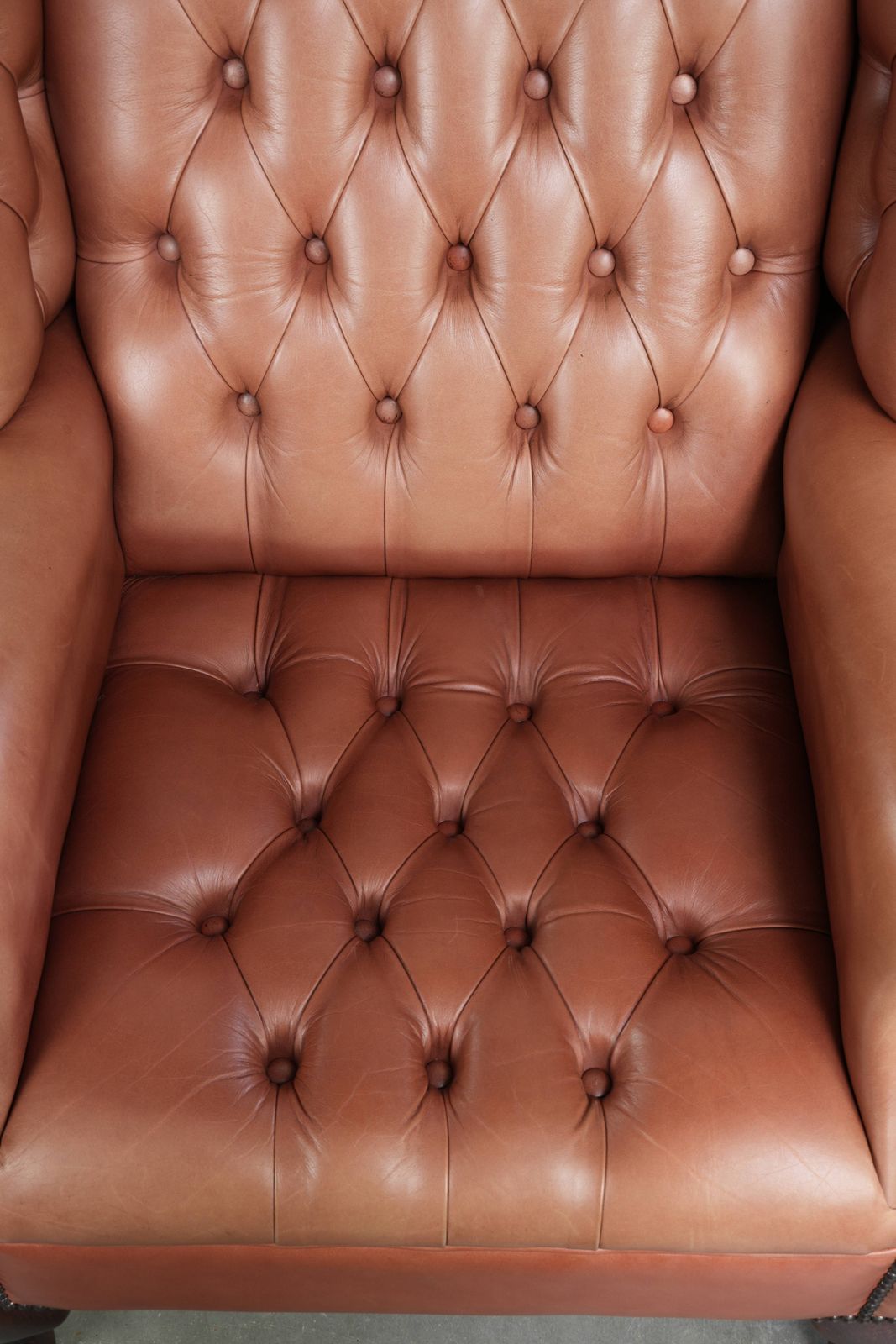 Klassieke Engelse Chesterfield-vleugelfauteuil met koeienhuid, knoopsluiting, mooie patina en fraaie kleuren. photo vinterior