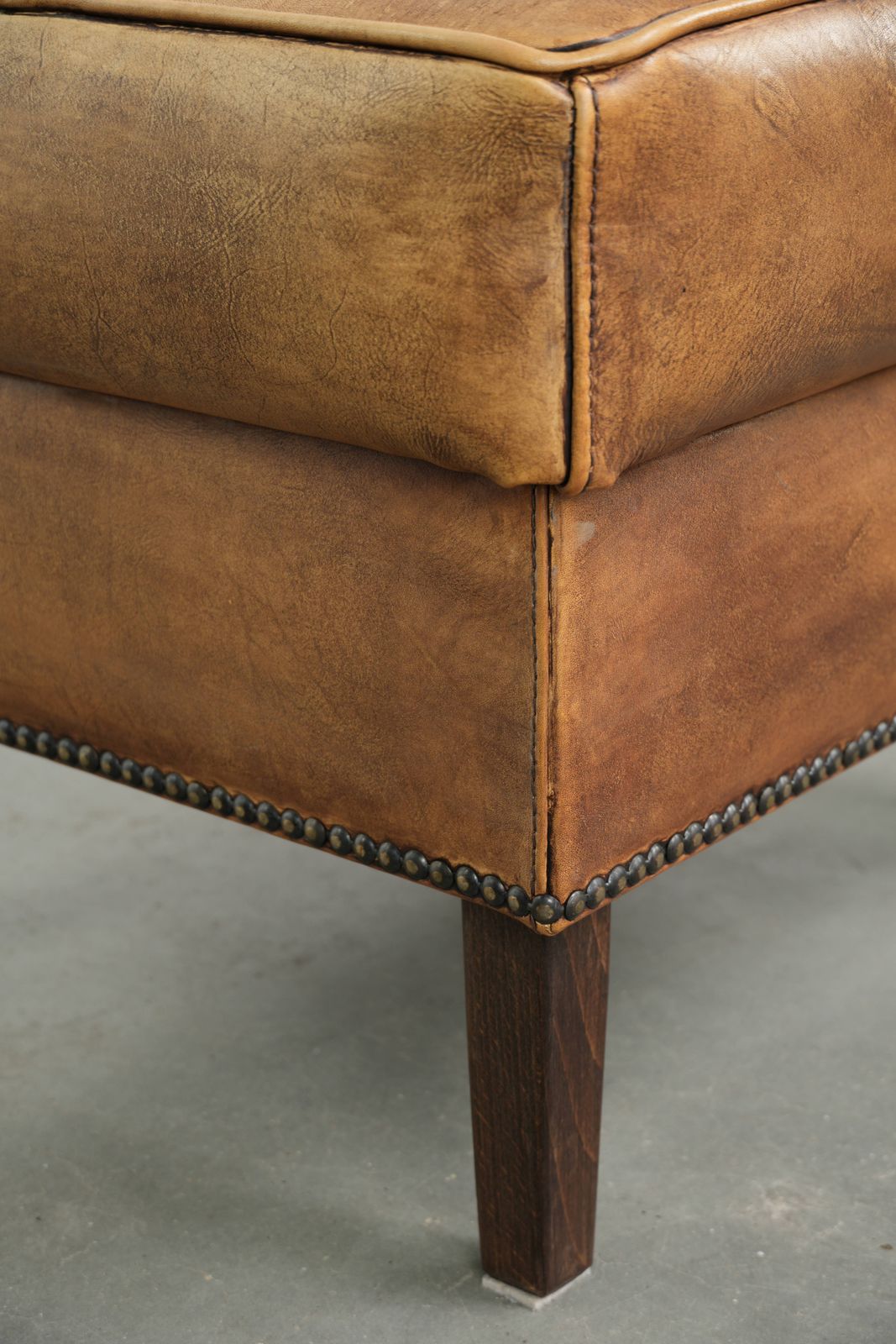 photo furniture Karaktervolle Ottomane van Koeienhuid met Mooie Patina, Afgewerkt met Sierspijkers.