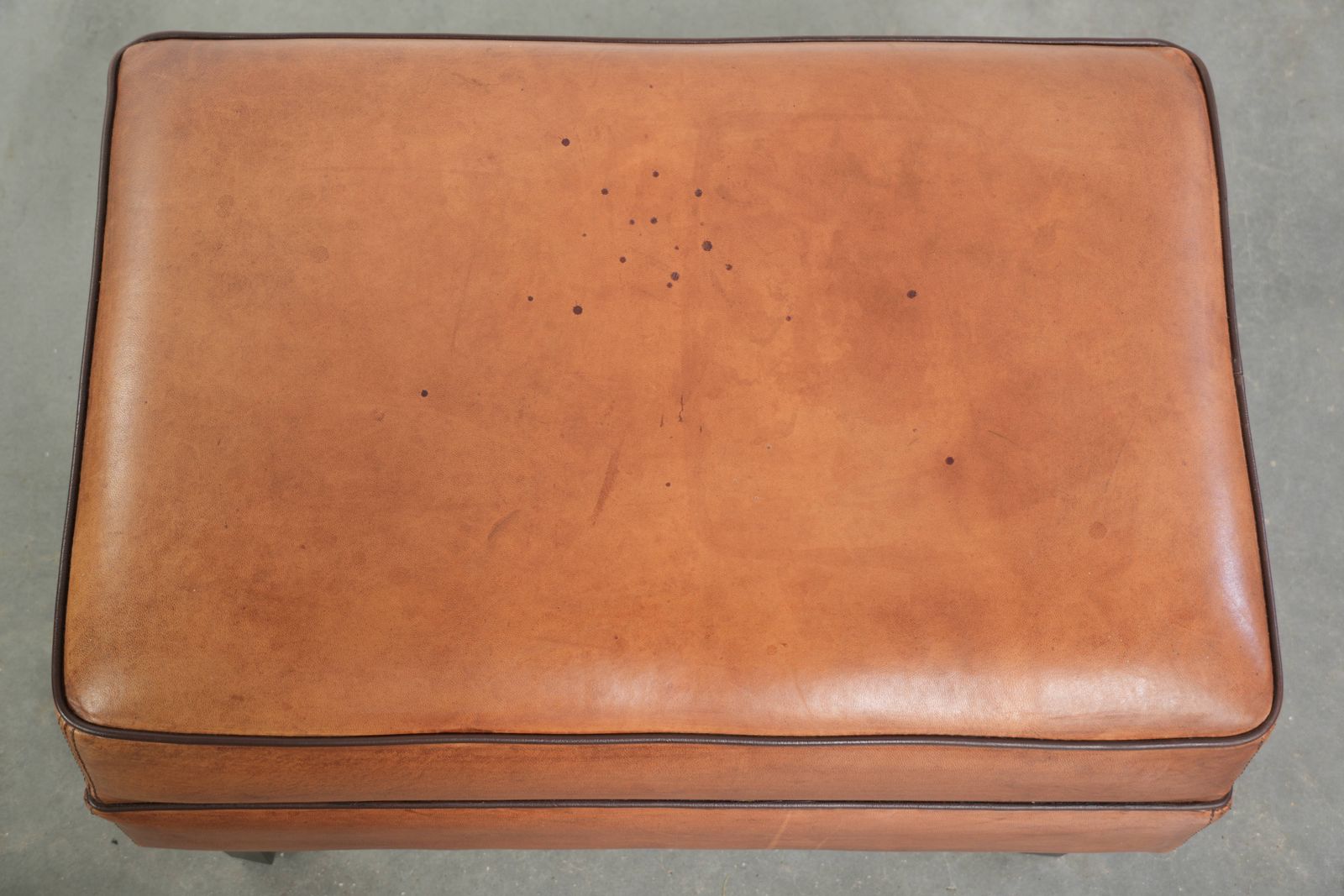 Handige schapenvacht poef met warme kleurstelling, afgewerkt met zwart biesje. photo vinterior