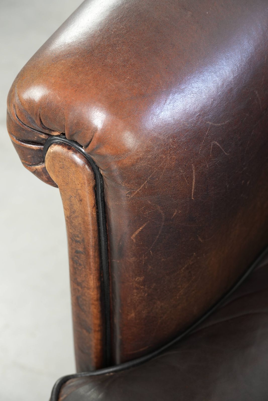 photo furniture Donkere schapenleren club fauteuil met uniek ontwerp en aantrekkelijke patina in Engelse stijl.