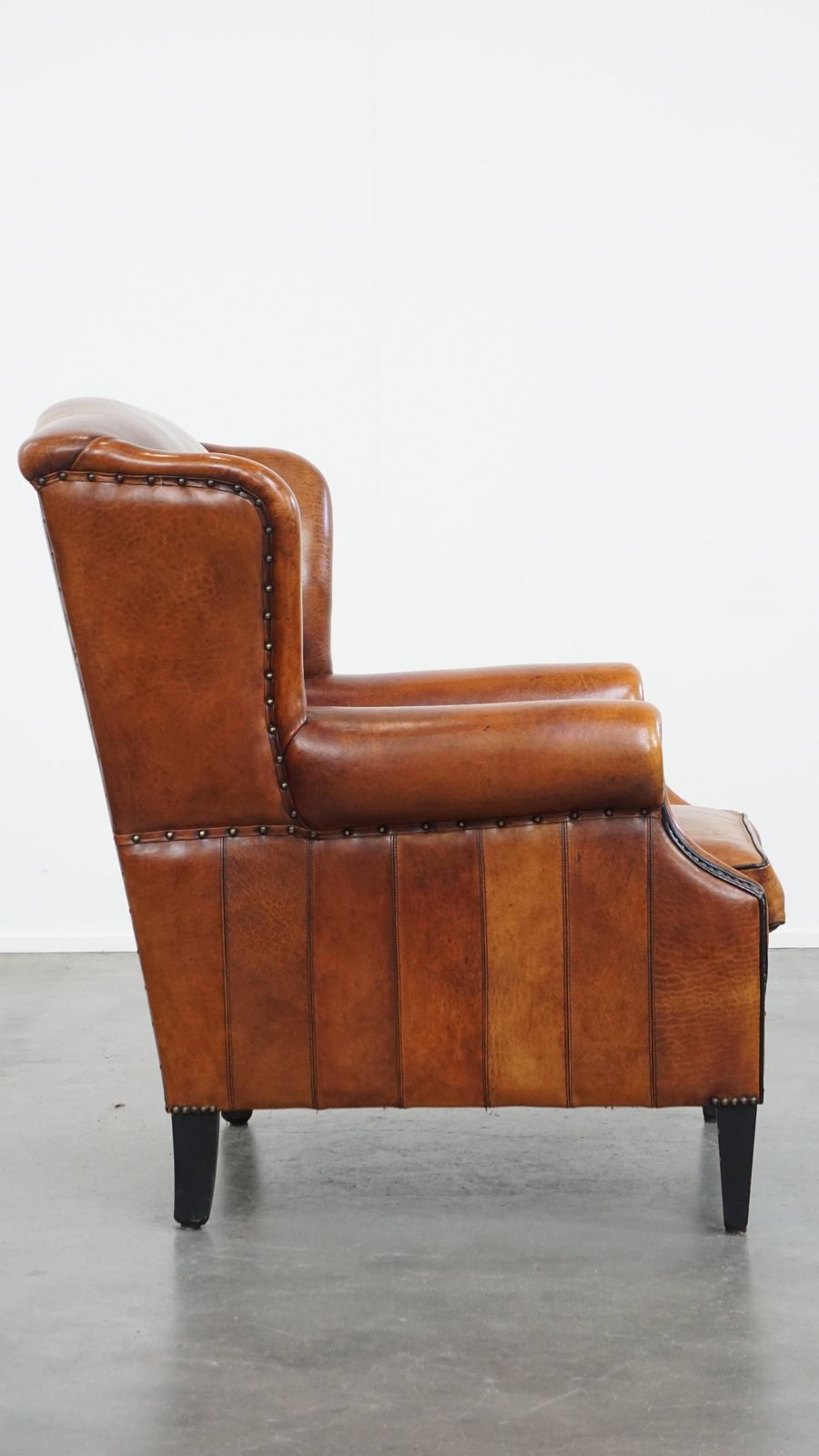 Comfortabele schapenvachten oorfauteuil met warme kleurstelling en afwerking met stiksels en zwart biesje. photo for sale