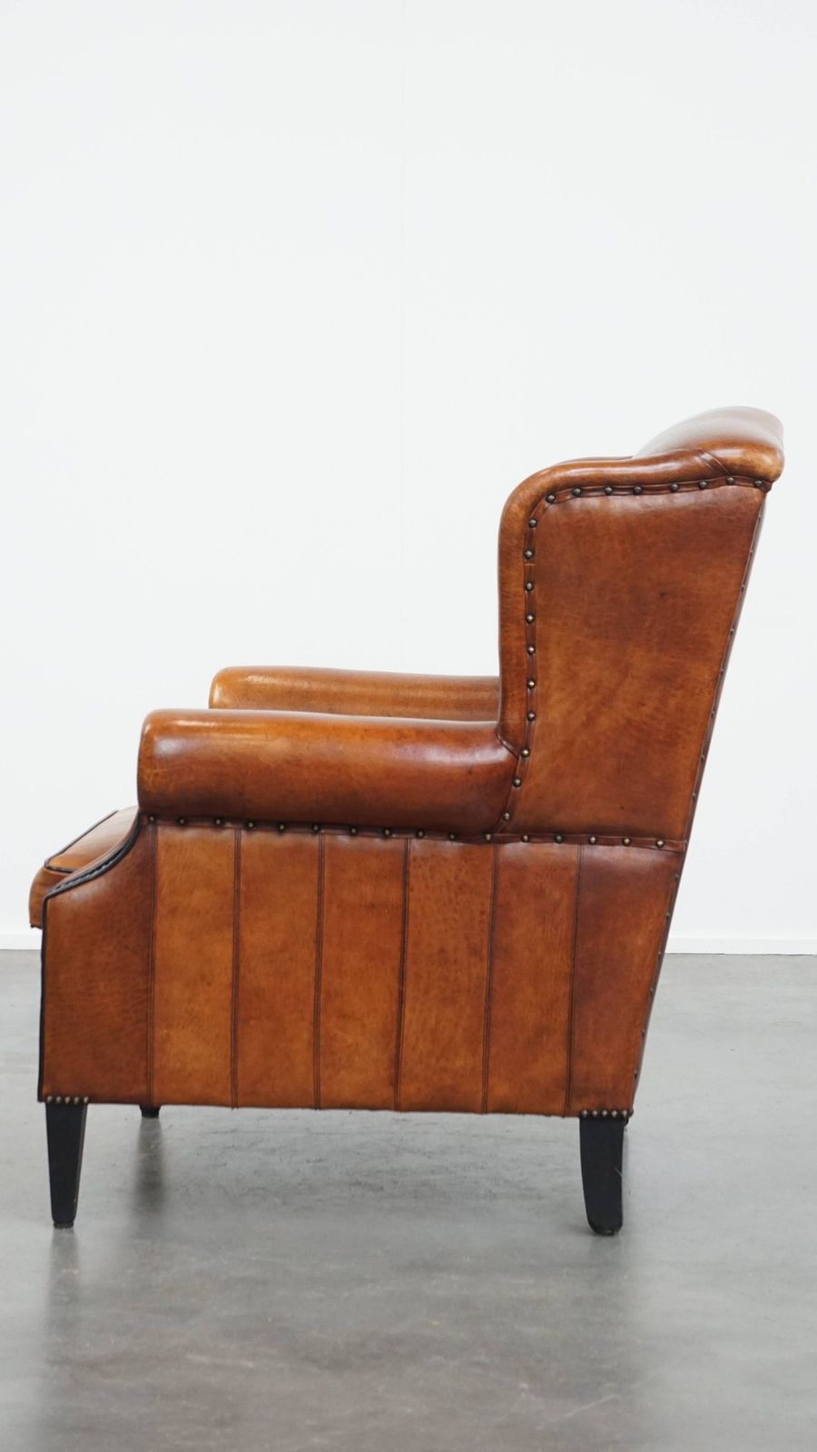 Comfortabele schapenvachten oorfauteuil met warme kleurstelling en afwerking met stiksels en zwart biesje. photo 1245.0
