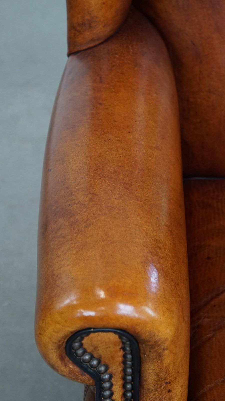 Comfortabele schapenvachten oorfauteuil met warme kleurstelling en afwerking met stiksels en zwart biesje. photo buy