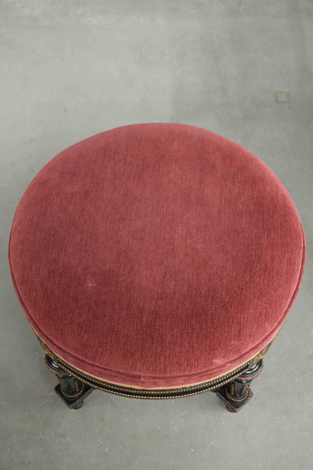Antieke Engelse kruk met rode stoffen zitting en zwart houten onderstel met goudkleurige details photo vinterior