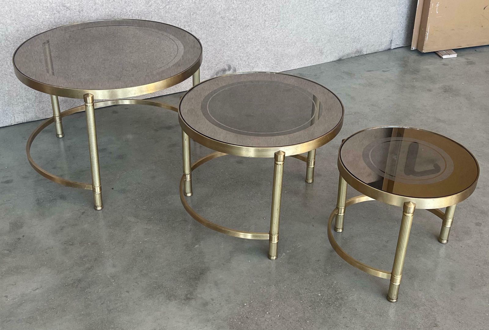 photo furniture Ensemble de trois tables gigognes rondes en laiton, plateaux en verre fumé rose