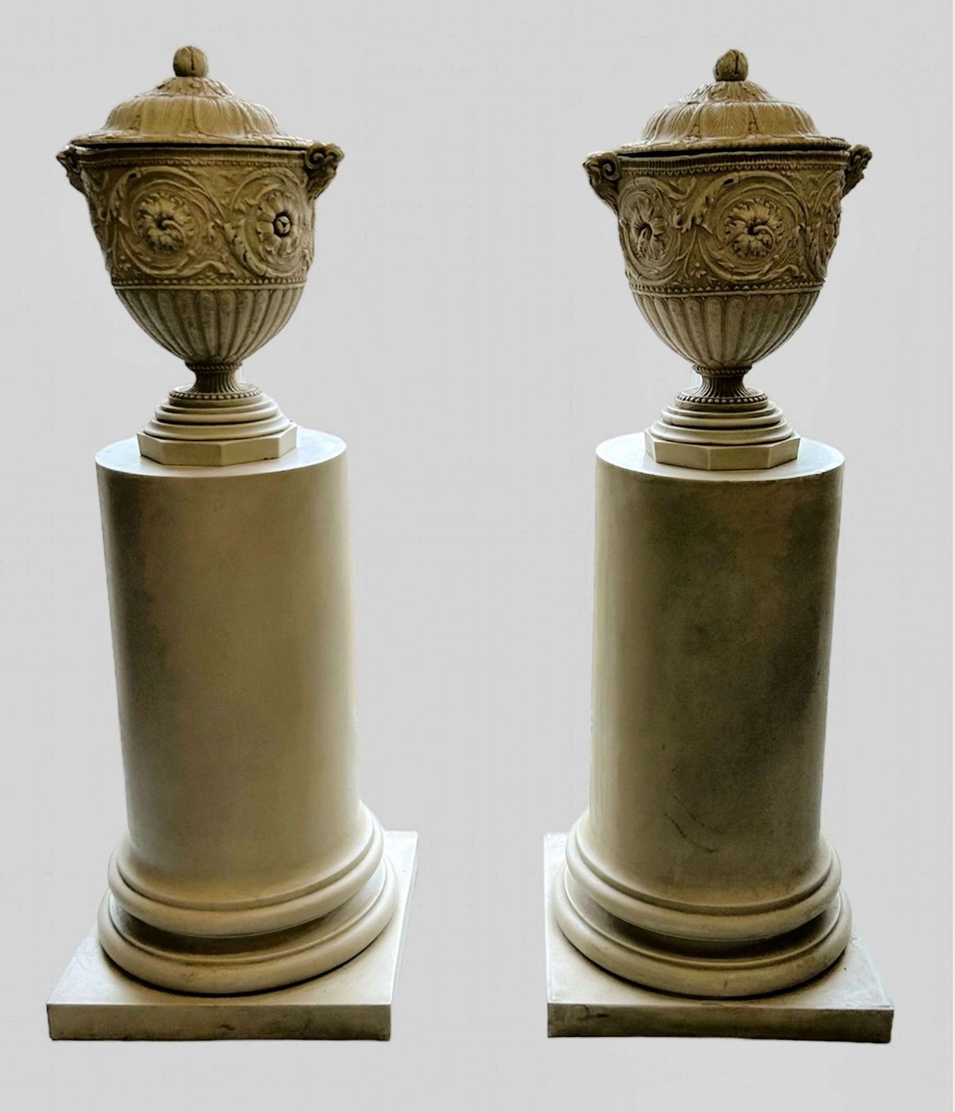 A Pair Of Decorative Pedestals With Lidded Urns