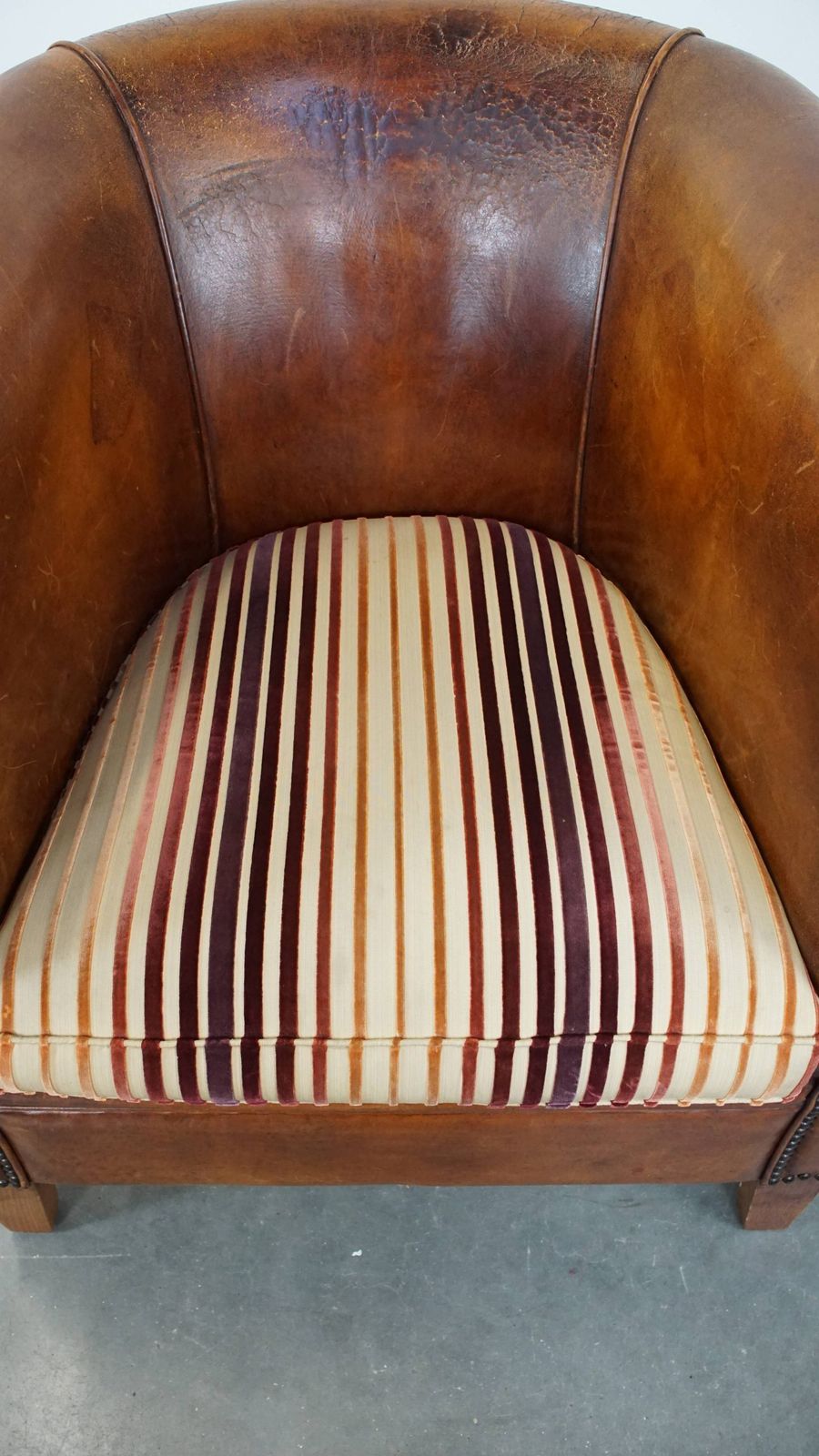 Characterful Vintage Cognac Colored Club Chair Made Of Sheepskin With A Colorful Fabric Seat Cushion photo vinterior