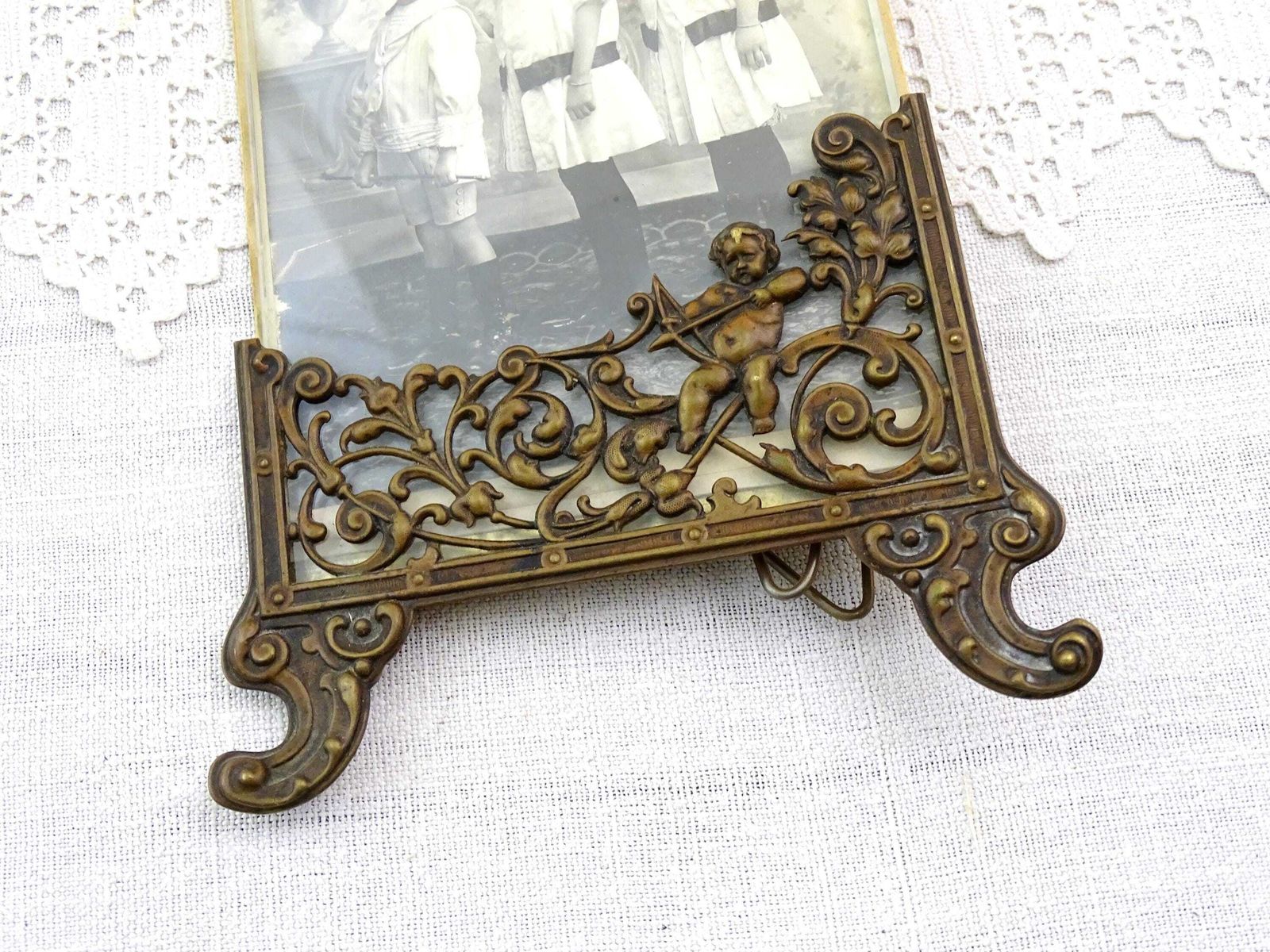 Antique French Free Standing Frame Decorated With A Cherub In Bronze Tone Embossed Metal And Black And White Photograph Sisters And Brother photo furniture