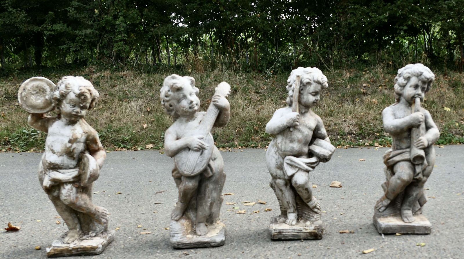 A Set Of 4 Weather Worn Cherub Statues With Instruments photo furniture