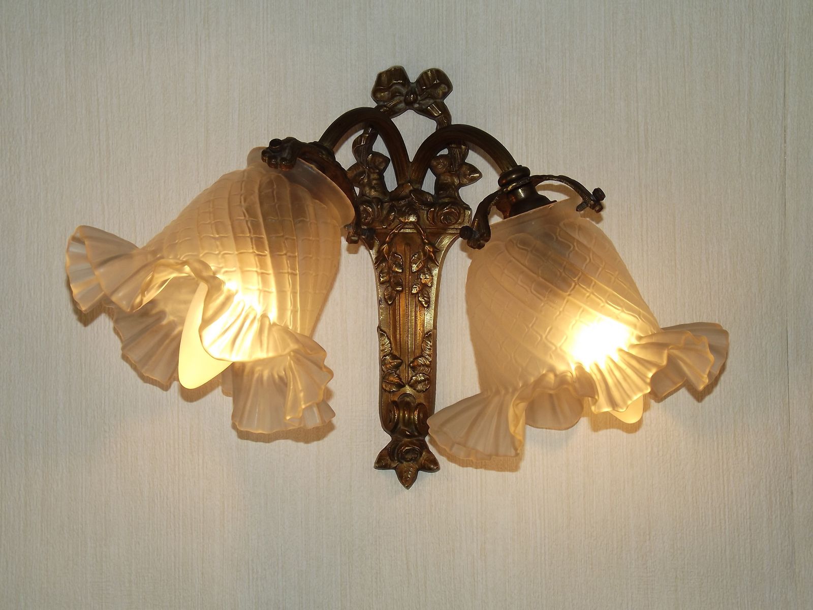 Applique murale double de style Rococo Revival français, en bronze, abat-jour en verre blanc à motifs. Luminaire d'époque. Double applique murale. Détail nœud et ruban.