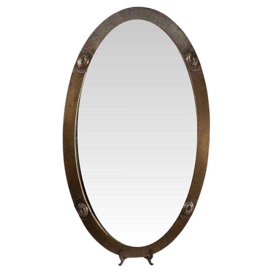 An Arts And Crafts Brass Hand Hammered Mirror With Four Celtic Style Details