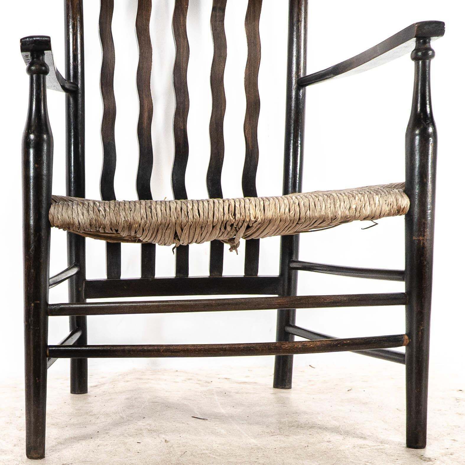 870.0 Liberty & Co. An Arts & Crafts Rush Seat Armchair With Wavy Shaped Back Slats photo