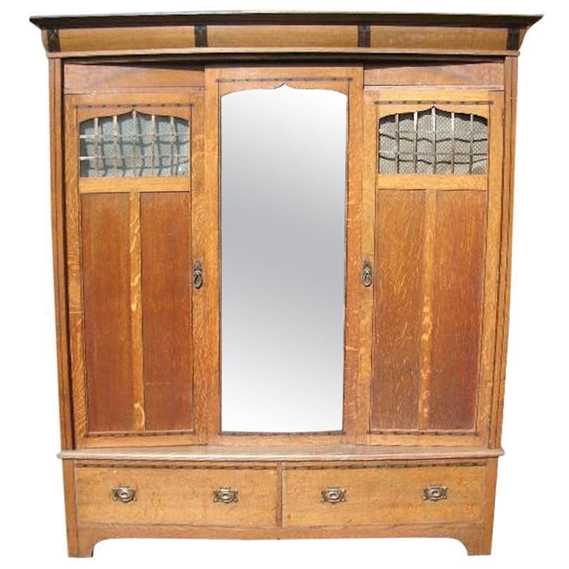 Gillows. An Arts & Crafts Oak Treble Wardrobe With Ebony Floral Inlays
