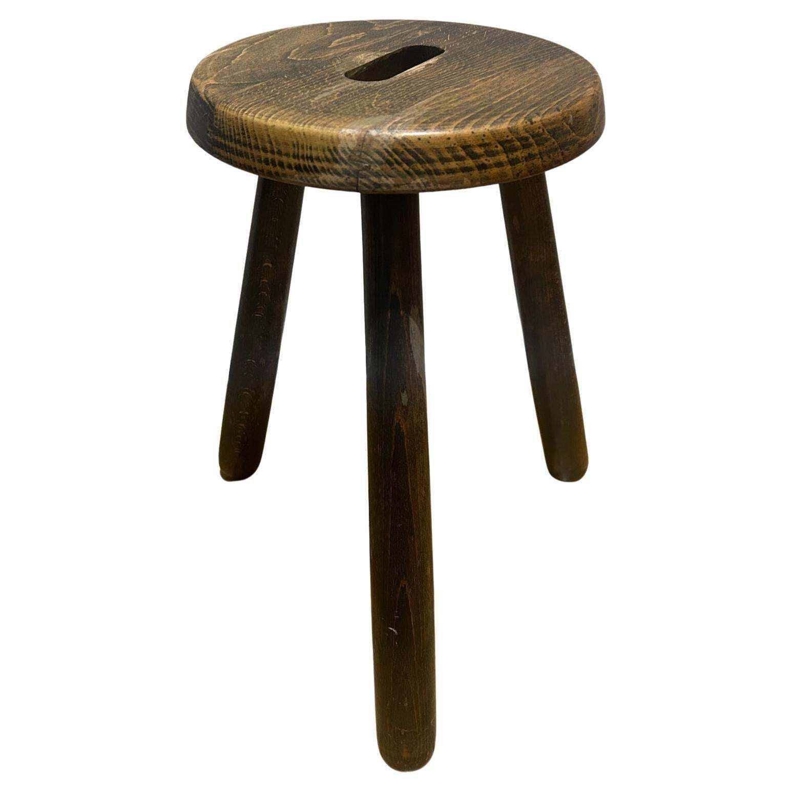 A Three Legged Wooden Stool With A Strong Brutalist