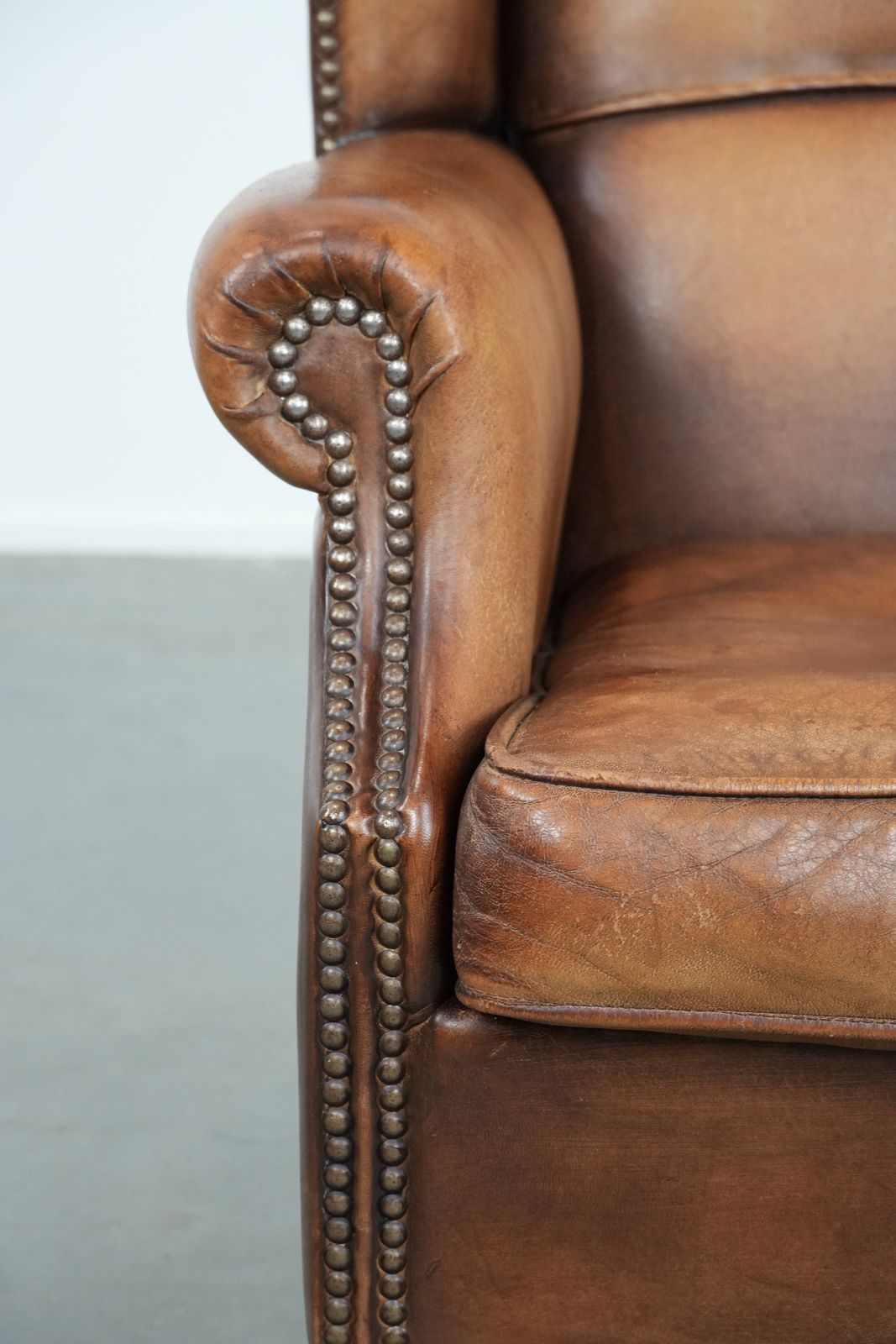photo furniture Charmante Schapenvacht Wingback Fauteuil In Warme Kleuren Met Decoratieve Sierspijkers