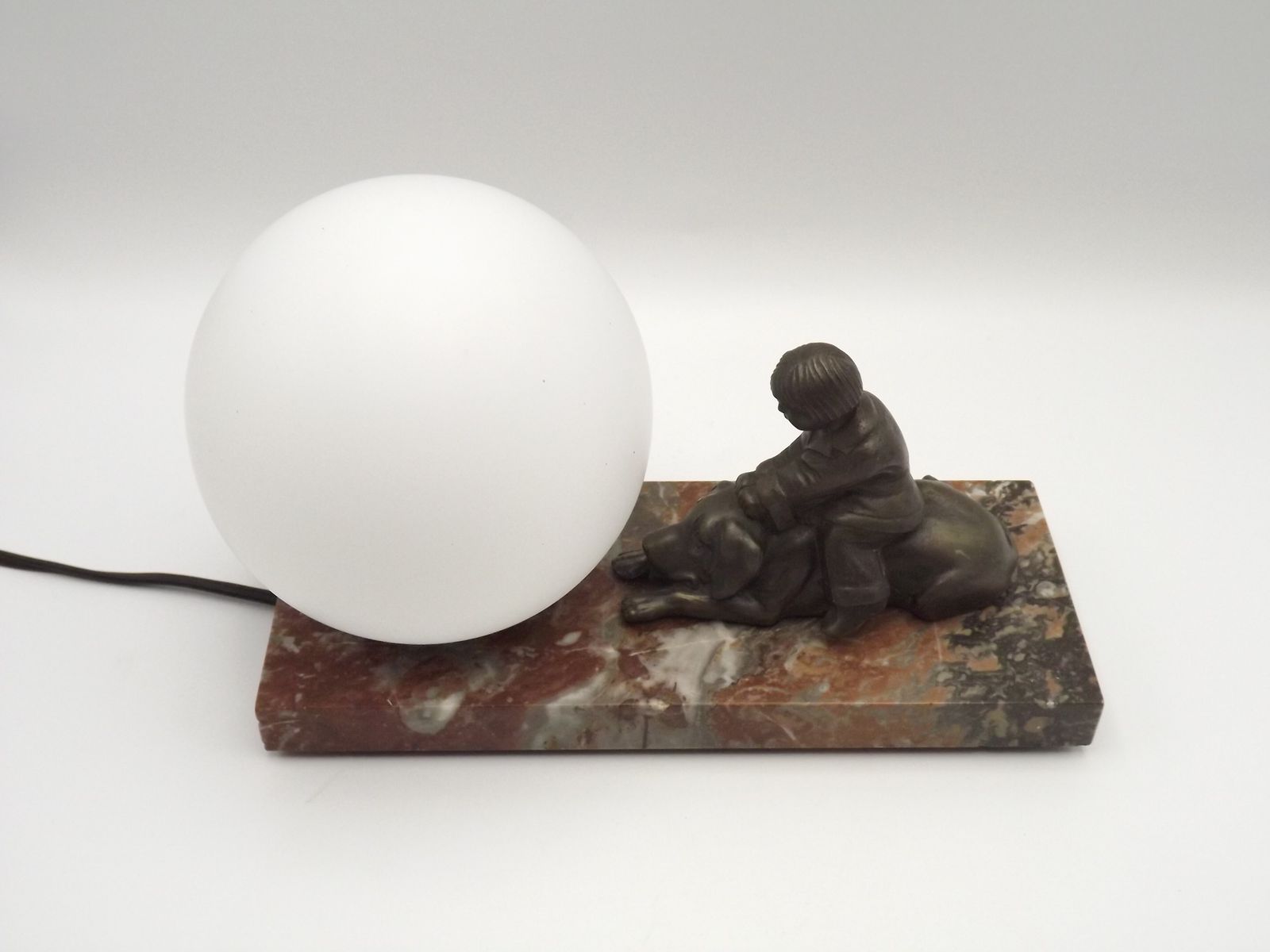 175.0 Franse art deco tafellamp met bruinmarmeren voet, kind-en-hond-figuur en witte opaline glazen bolkap photo