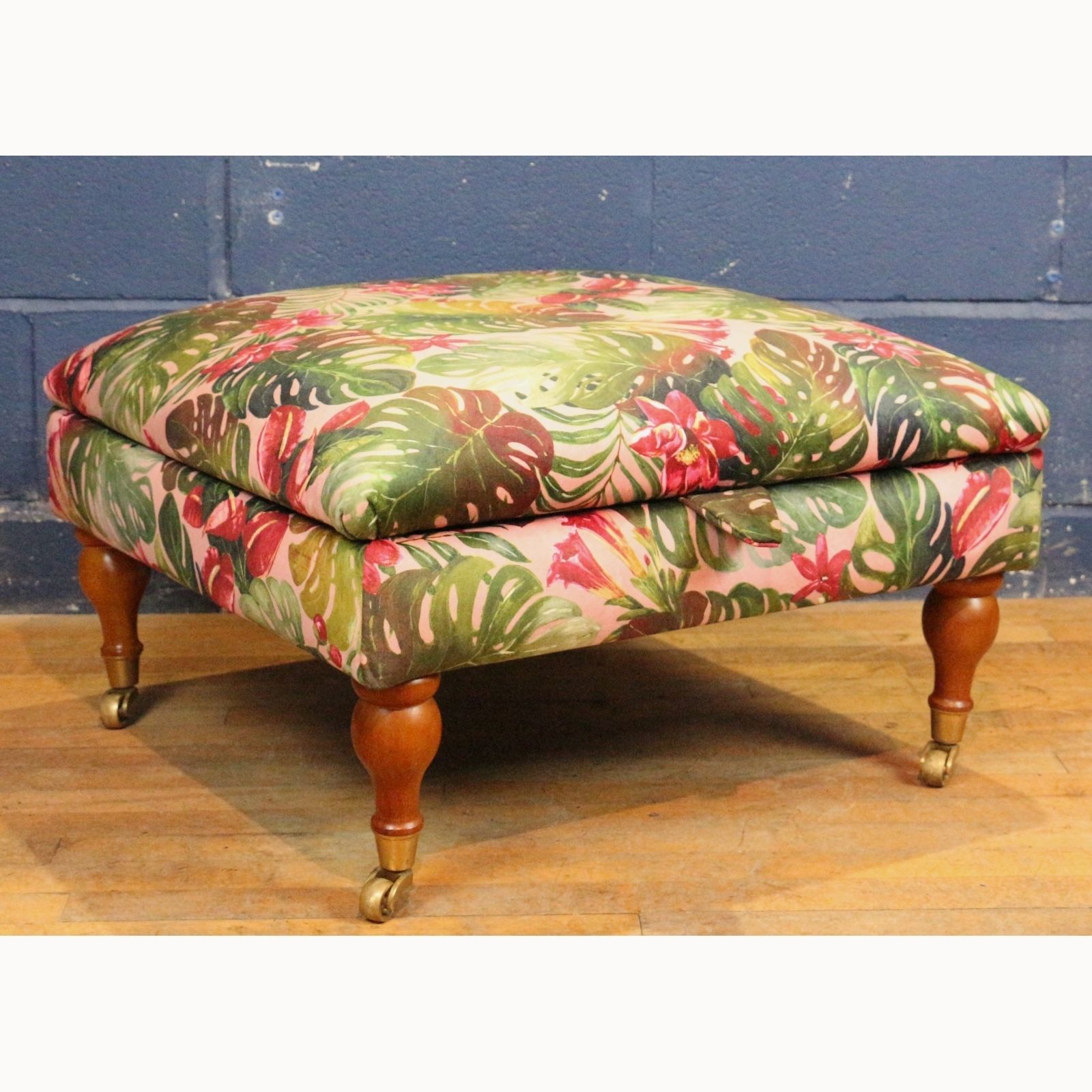 A Large Square Footstool Or Ottoman, Reupholstered In Stylised Material Raised On Turned Supports