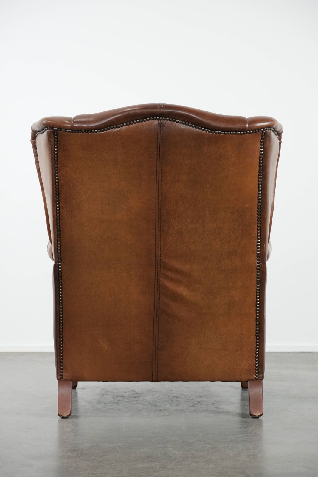 Timeless Cognac Colored Wing Armchair In English Style Made Of Cowhide Leather, Finished With Decorative Studs And Beautiful Details. photo Furniture