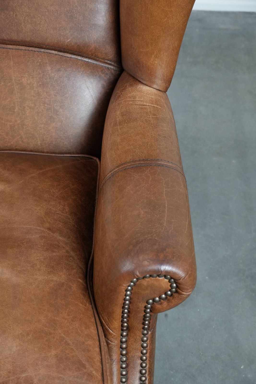Timeless Cognac Colored Wing Armchair In English Style Made Of Cowhide Leather, Finished With Decorative Studs And Beautiful Details. photo vintage