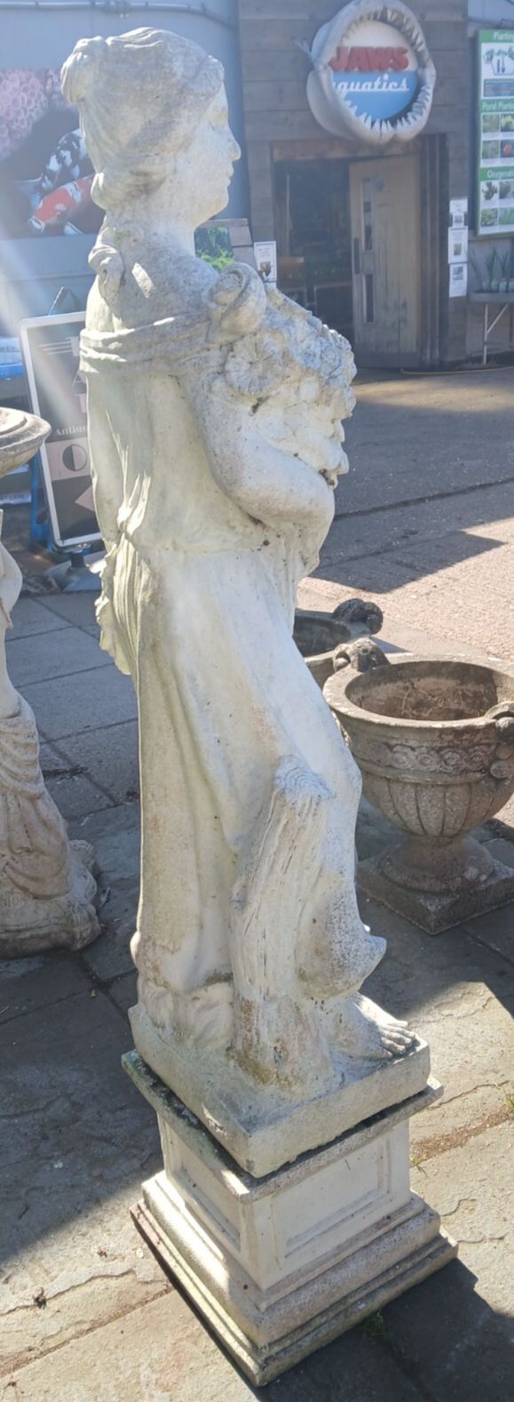 Weathered Concrete Statue Of Female Carrying Flowers photo for sale