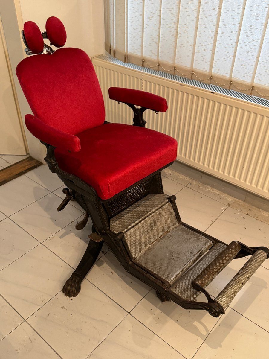 Kappersstoel met rode bekleding en verstelbare voetensteun photo vintage
