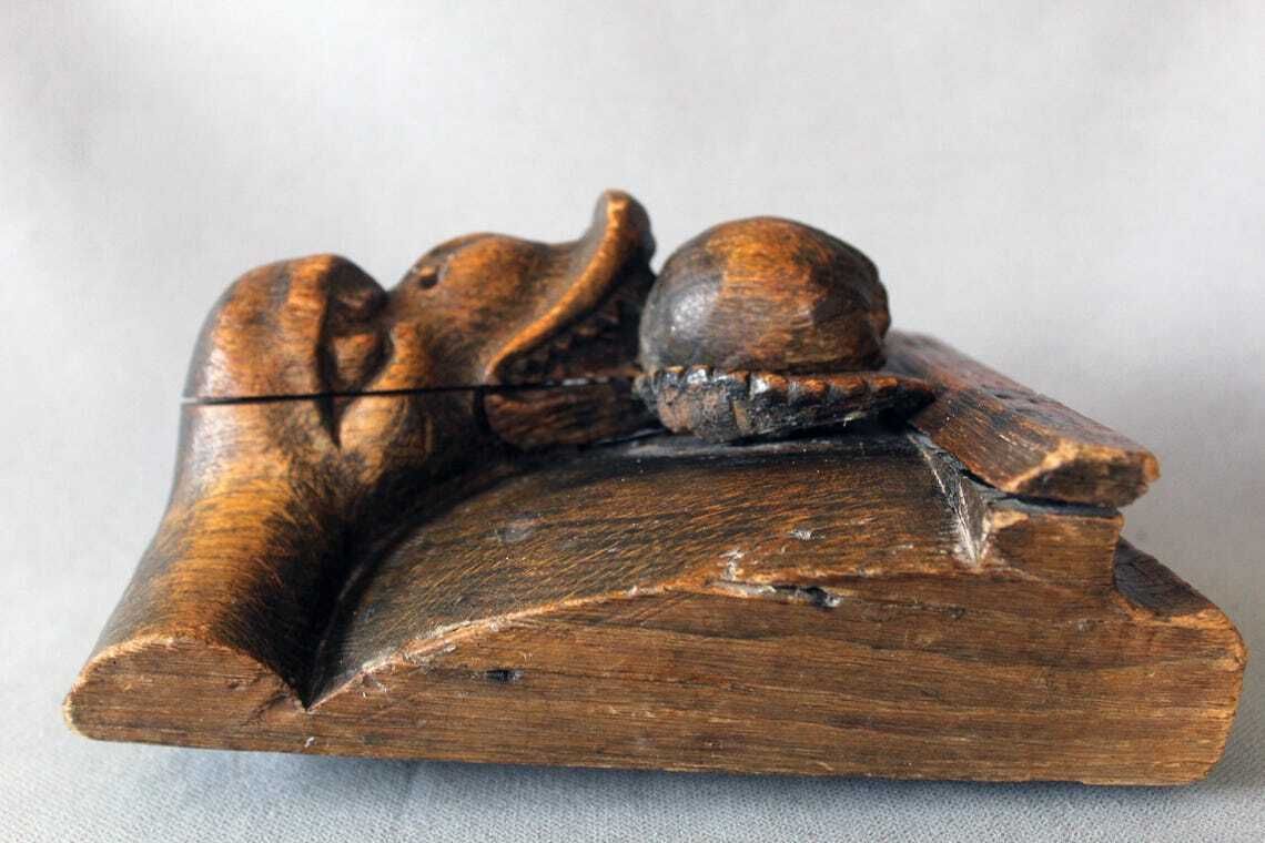 photo for sale Groot antiek houten ornament in de vorm van een slangenkop met tanden die een appel of granaatappel eet, driedimensionaal, handgesneden, gotische architectuur
