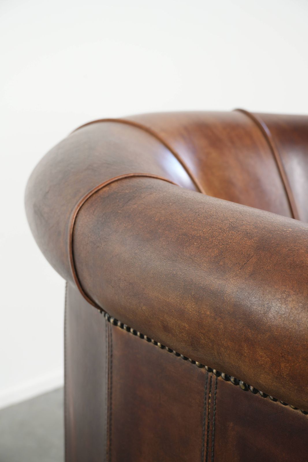 photo for sale Stevige en karaktervolle clubfauteuil in schapenleer met een mooie patina, afgewerkt met decoratieve nagels.