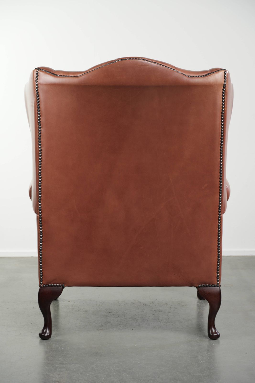 Klassieke Engelse Chesterfield-vleugelfauteuil met koeienhuid, knoopsluiting, mooie patina en fraaie kleuren. photo Meubels