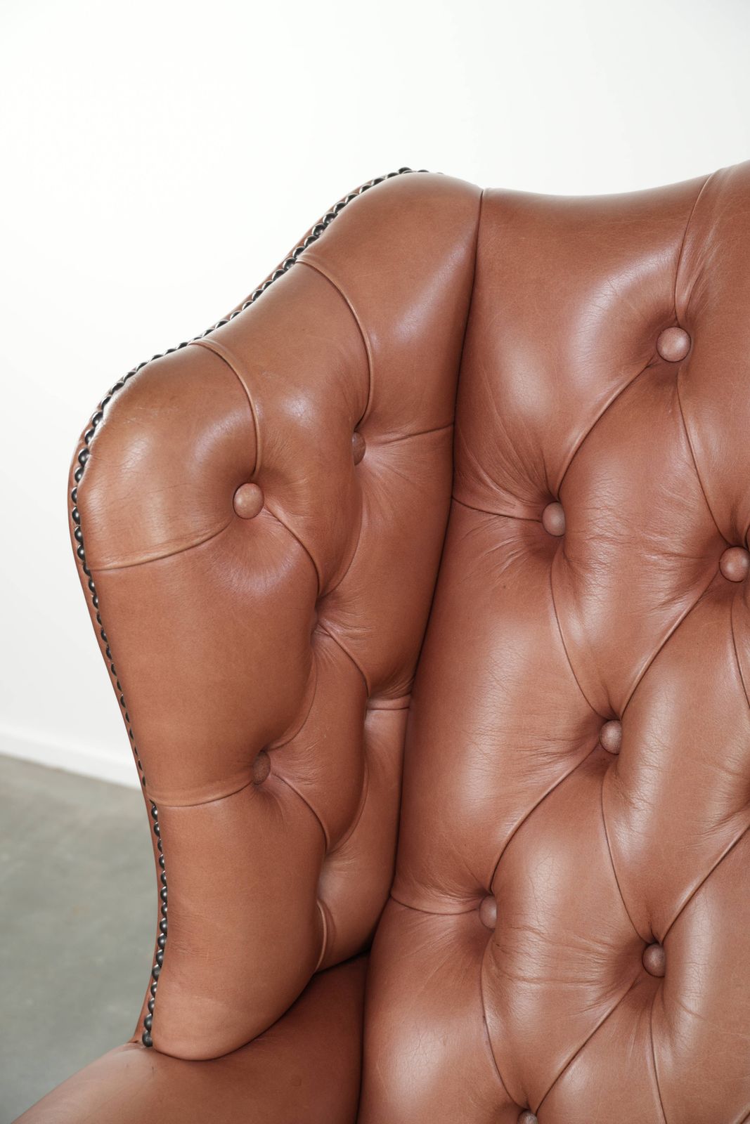 photo furniture Klassieke Engelse Chesterfield-vleugelfauteuil met koeienhuid, knoopsluiting, mooie patina en fraaie kleuren.