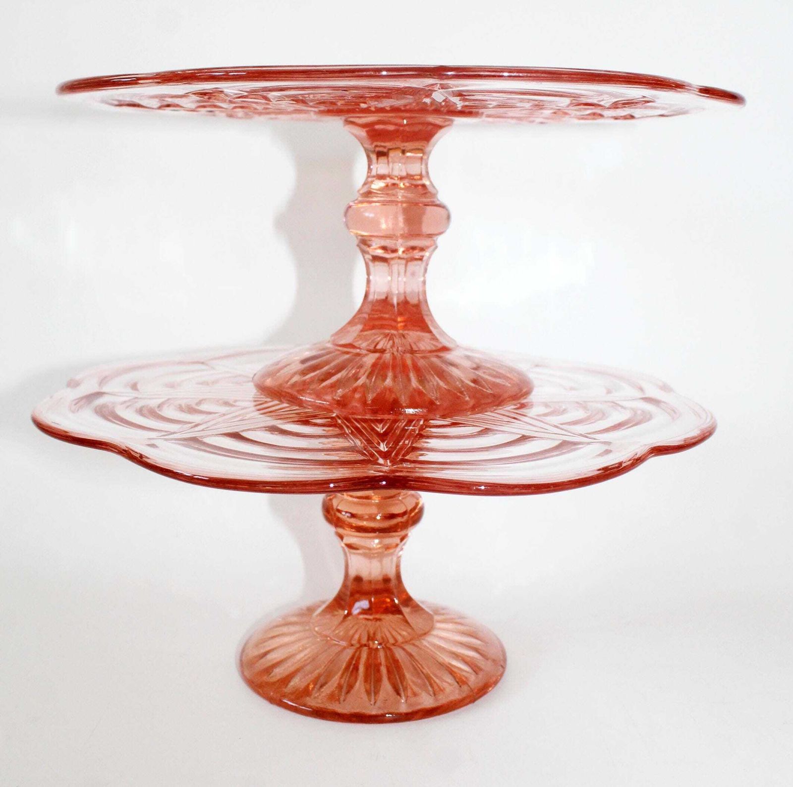 photo vintage Lot de deux présentoirs à gâteau Art déco en verre rose rosaline, plateau sur pied, verre pressé à motif géométrique en relief