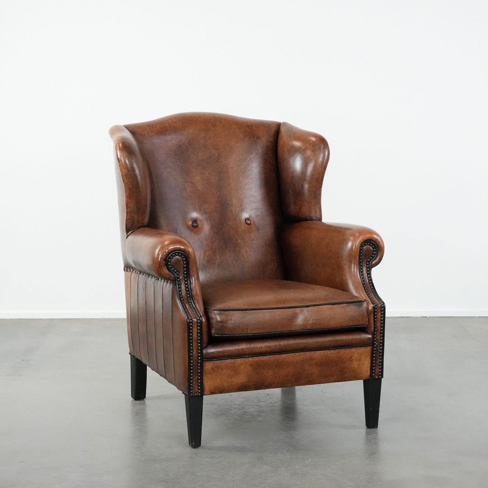Timeless And Comfortable Sheepskin Wing Armchair With Beautiful Colors And A Finish With Decorative Nails And Black Piping.
