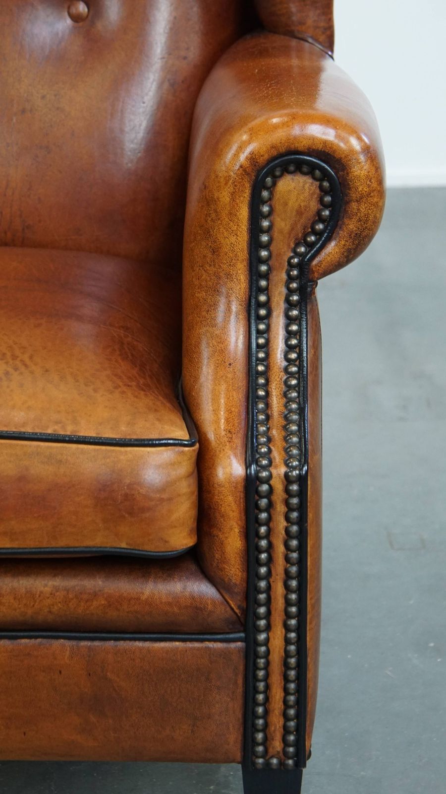 photo for sale Comfortabele schapenvachten oorfauteuil met warme kleurstelling en afwerking met stiksels en zwart biesje.