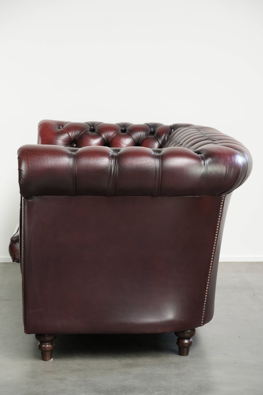 Tijdloze Chesterfield 2,5-zitsbank van koeienhuid in oxblood rood met mooie patina photo Meubels