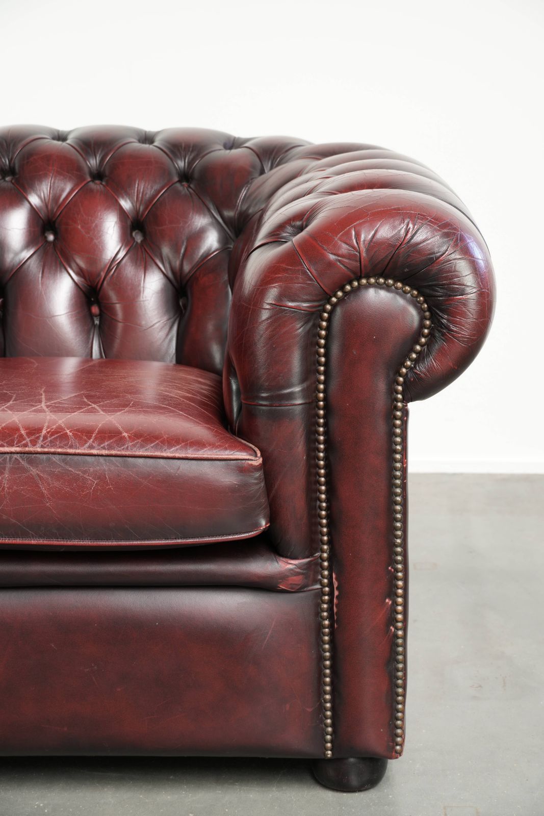 photo furniture Chique Engelse Chesterfield Club Fauteuil met Gebruikssporen in een Tijdloze Rode Kleur