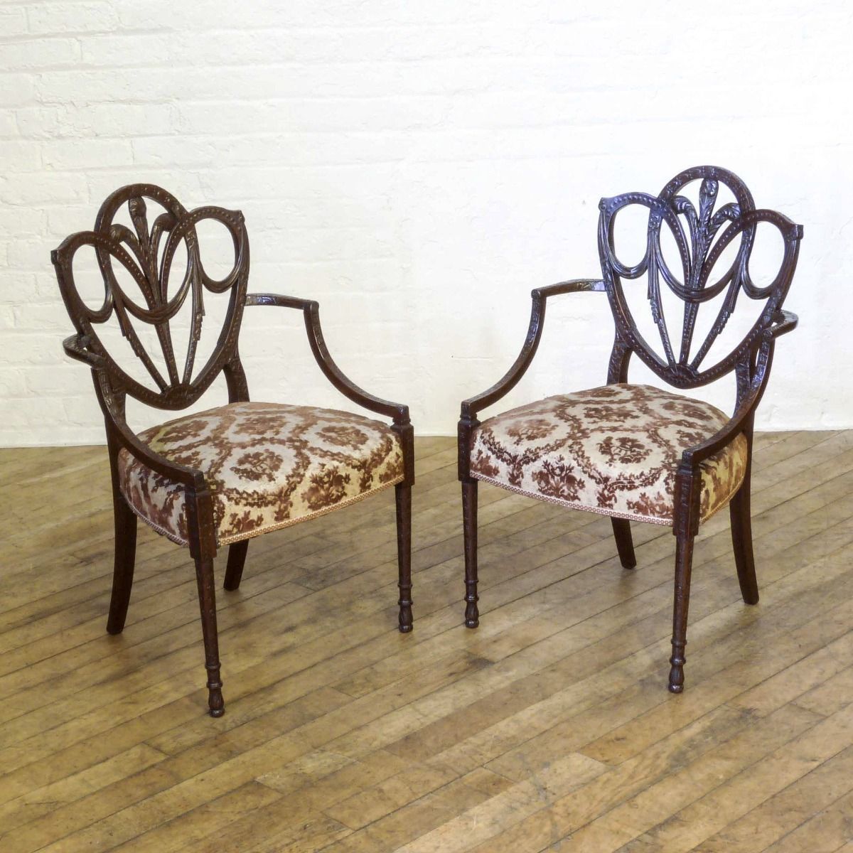 A Pair Of Edwardian Mahogany Armchairs In The Manner Of Hepplewhite. Profusely Carved With Foliage, Flowers, Ribbons And Swags. The Central Shield Bac photo furniture