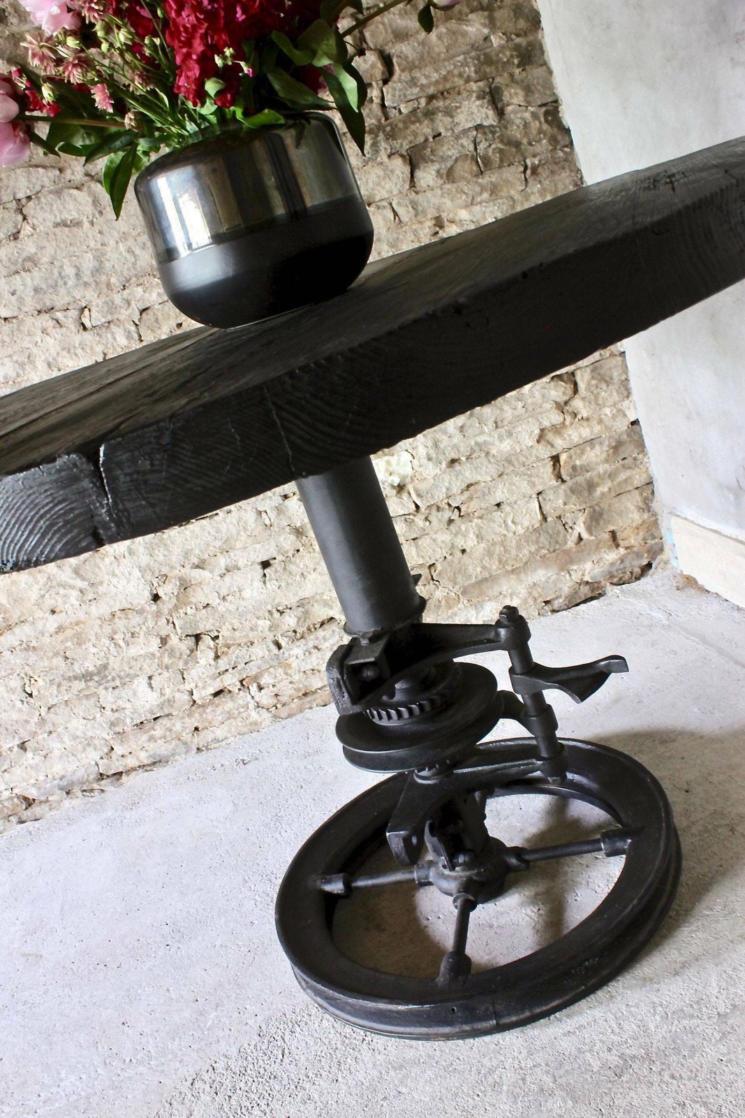 photo furniture Shift Reclaimed Chunky Scorched Timber Circular Table With A Heavy Pedestal Base Made Out Of An Old Gear System