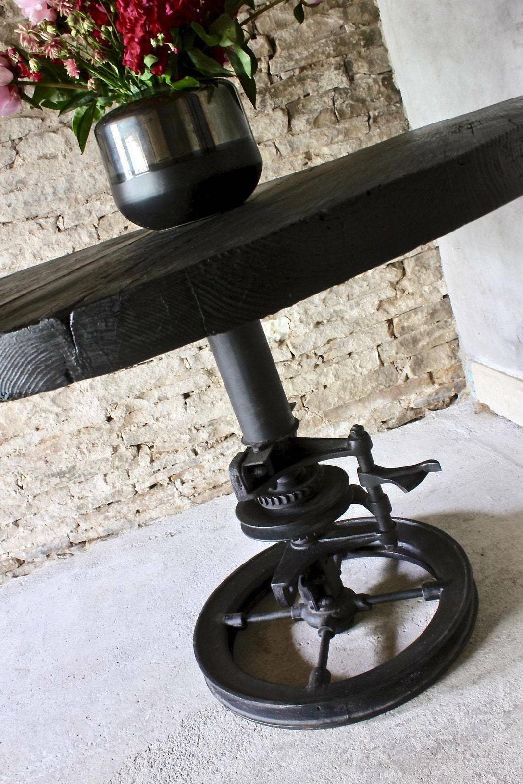 photo furniture Shift Reclaimed Chunky Scorched Timber Circular Table With A Heavy Pedestal Base Made Out Of An Old Gear System