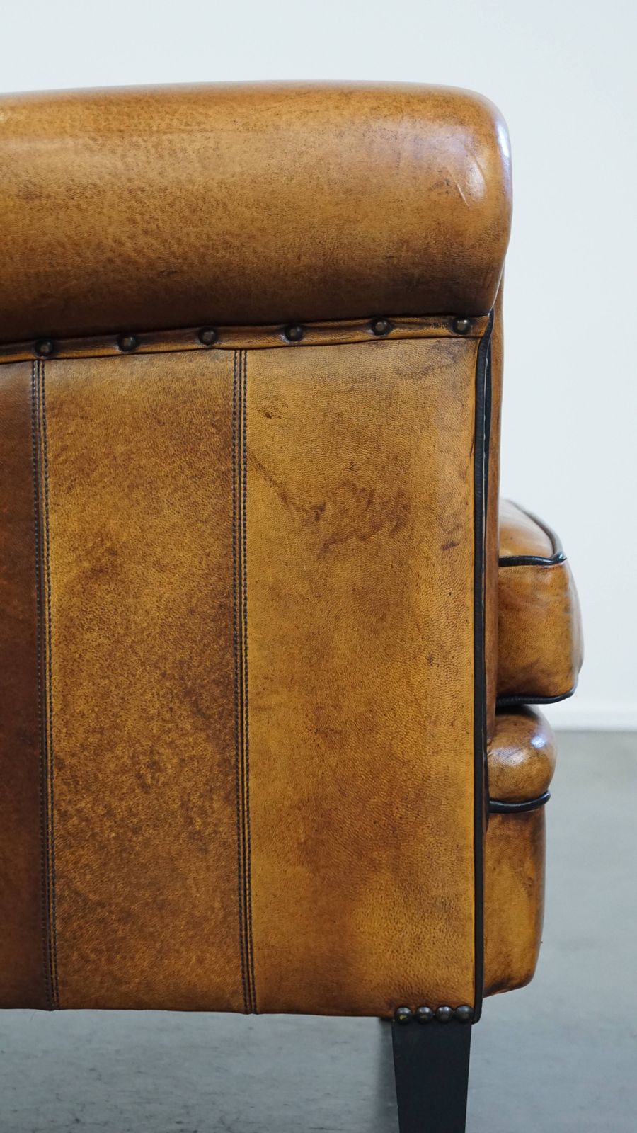 photo vinterior Goed onderhouden schapenleren design fauteuil, luxueus afgewerkt met siernagels en zwart biesje