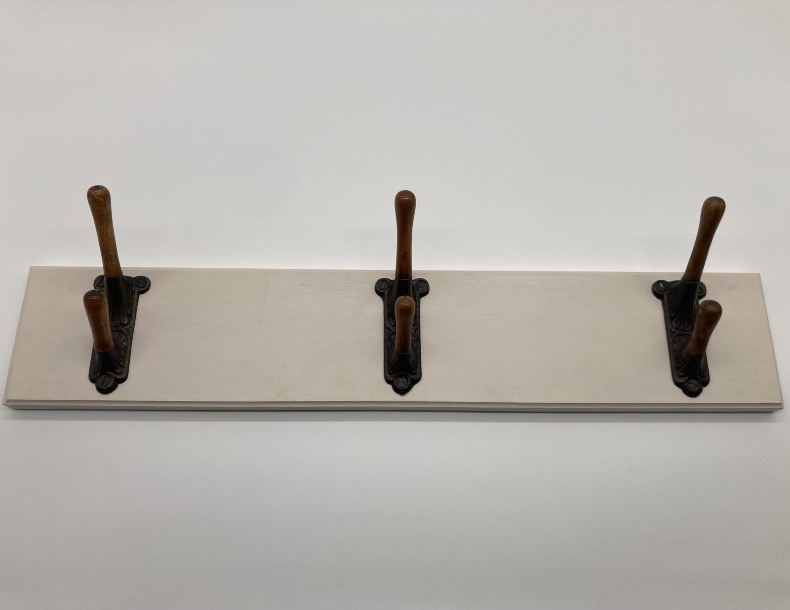A Set Of Three Victorian Iron And Oak Coat Hooks Mounted On A Board