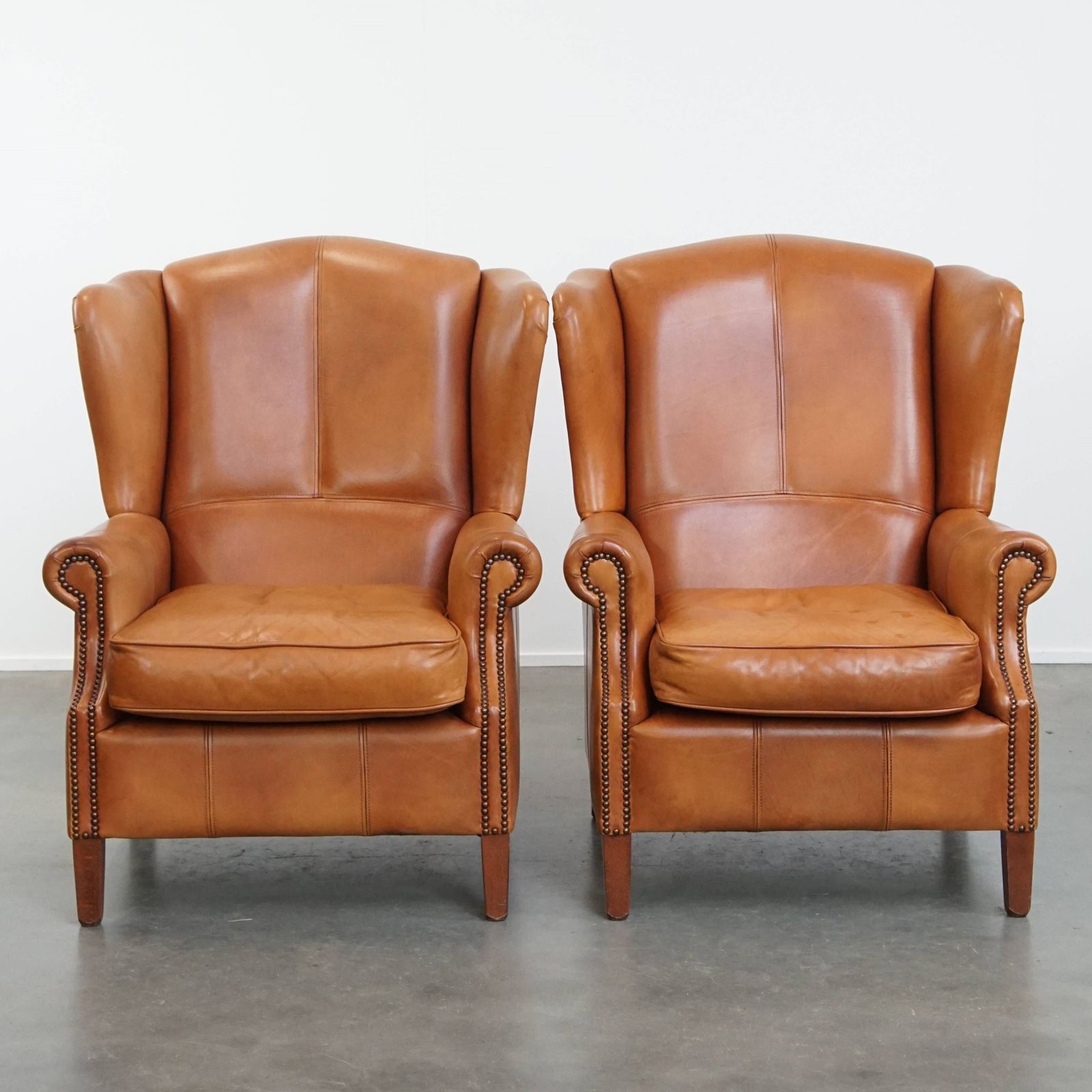 Classic And Unique Set Of 2 Cowhide Wing Chairs Finished With Decorative Nails And Beautiful Details