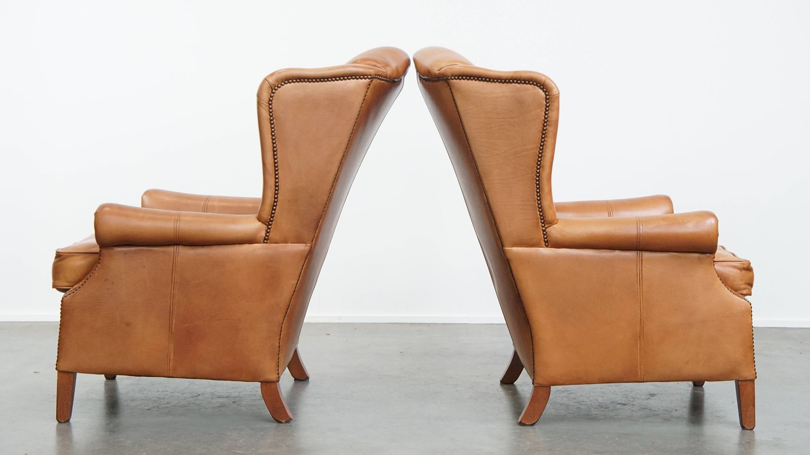 Klassieke Set Van 2 Koehuidenleren Wingback Fauteuils Met Decoratieve Nagels En Verfijnde Details photo Meubels