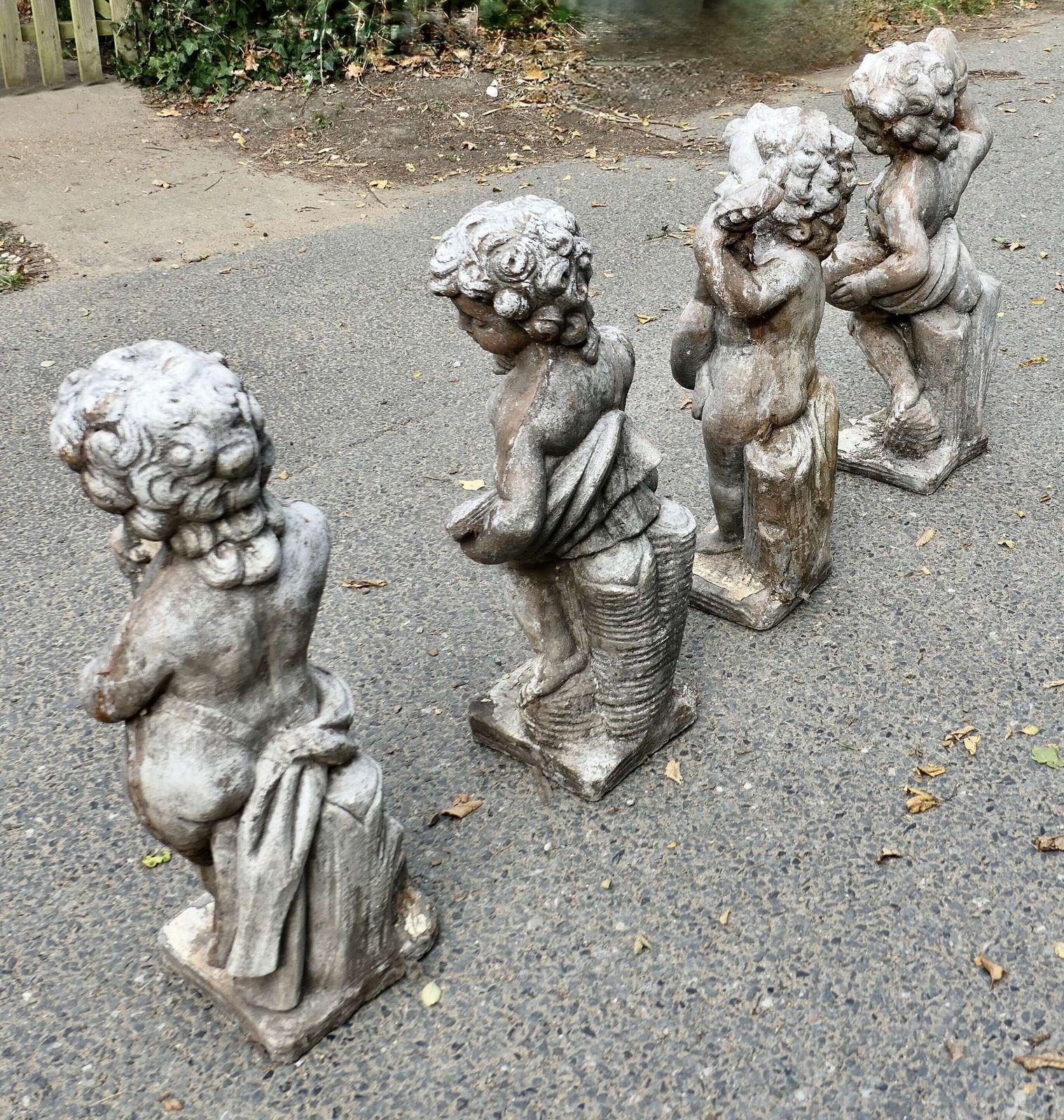 A Set Of 4 Weather Worn Cherub Statues With Instruments photo for sale
