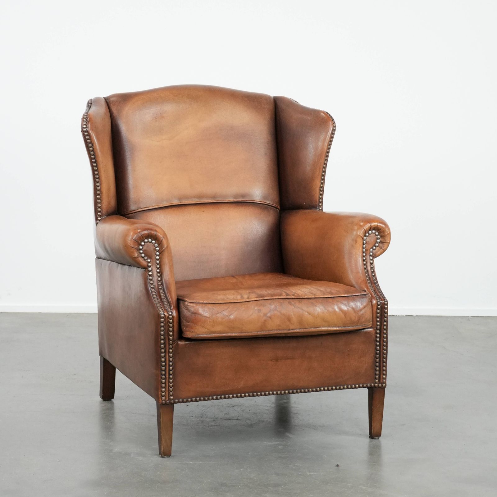 Charmante Schapenvacht Wingback Fauteuil In Warme Kleuren Met Decoratieve Sierspijkers