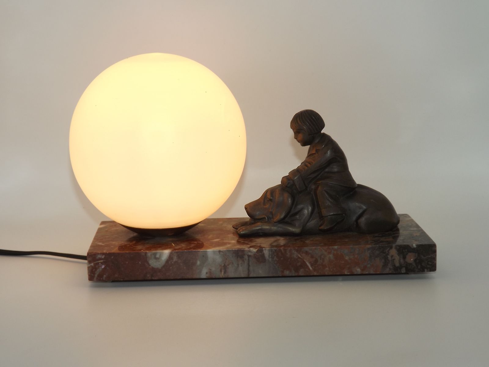 photo buy Franse art deco tafellamp met bruinmarmeren voet, kind-en-hond-figuur en witte opaline glazen bolkap